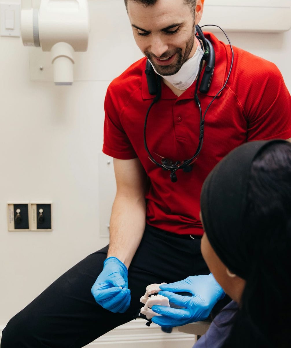 Dentist using a tooth model to explain to a patient when a dental crown is recommended