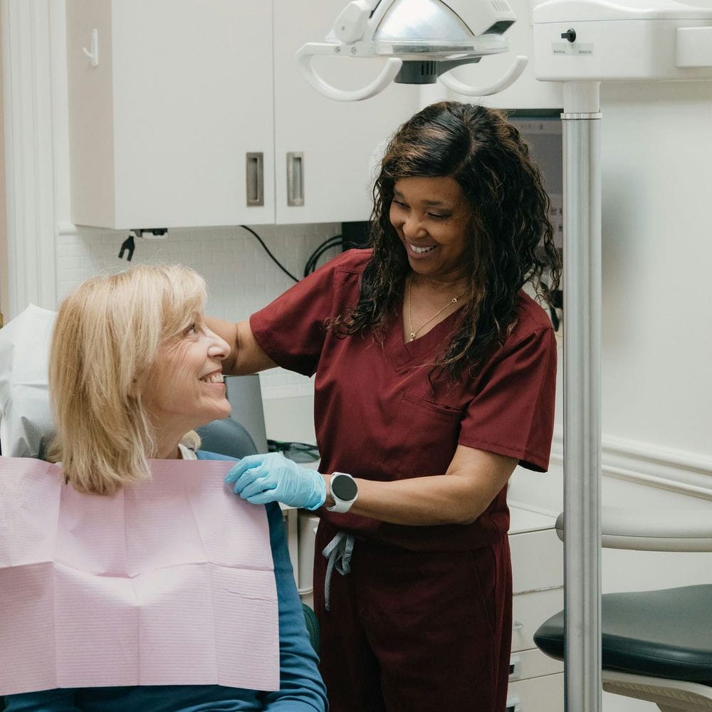 Dental assistant reassuring a relaxed, laughing patient in the chair during anxiety-aware cosmetic care