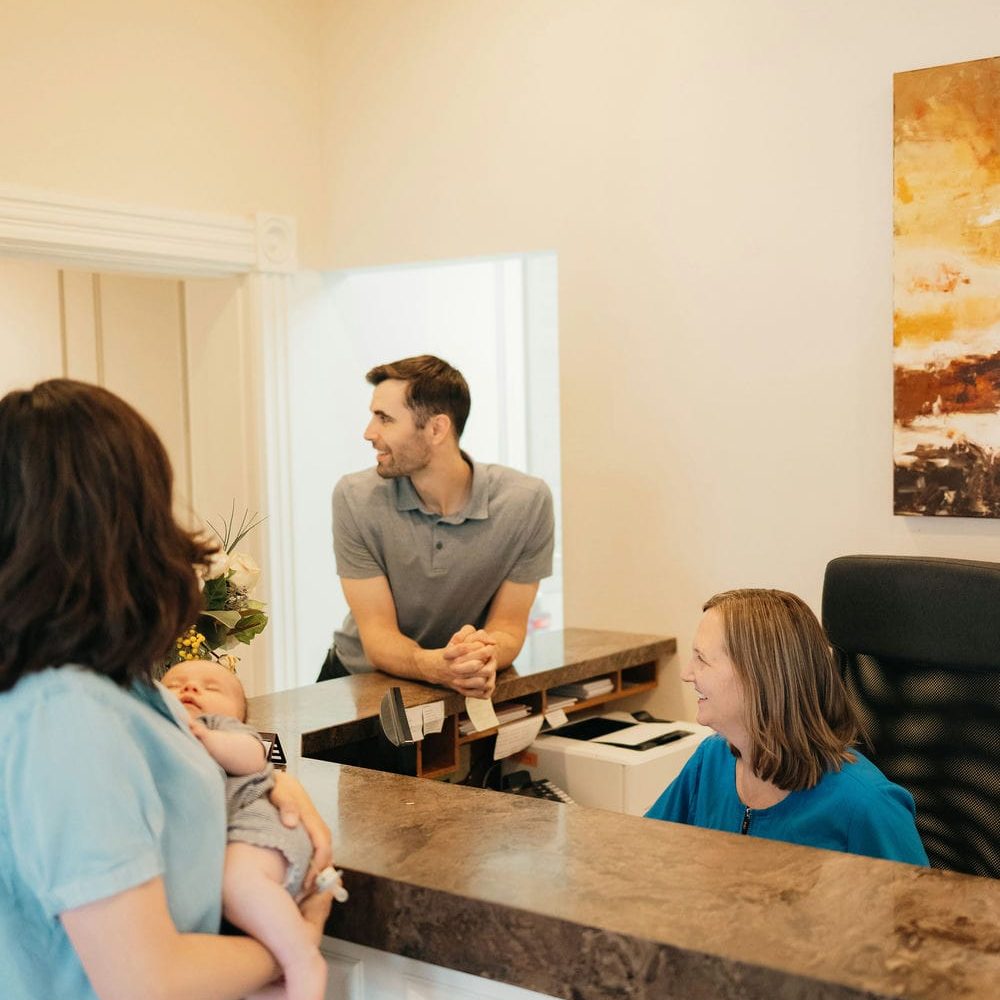 Mother holding her baby while booking the family's next appointment at a Markham dental office