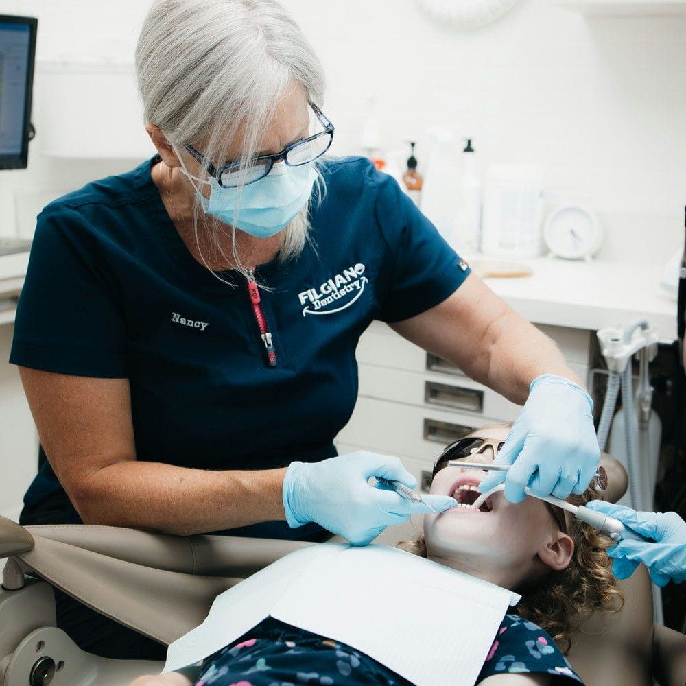 Hygienist gently cleaning a young girl's teeth during a children's dental appointment in Markham