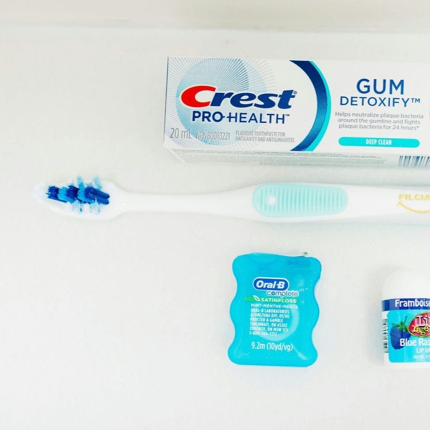 Toothbrush, floss and toothpaste laid out to show the daily routine that keeps a dental bridge healthy
