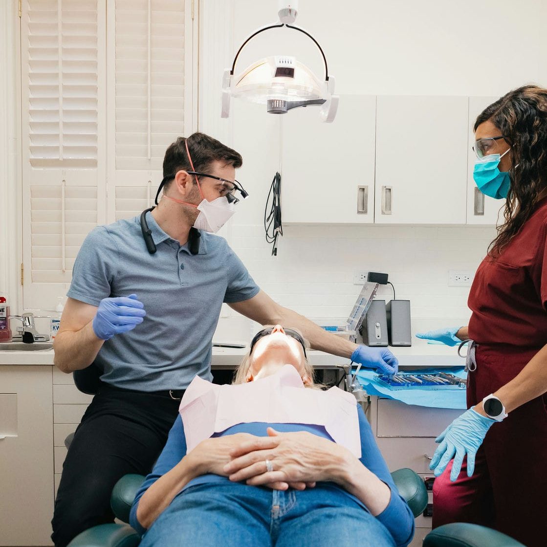 Dentist and assistant preparing beside a patient, keeping an implant appointment calm and comfortable