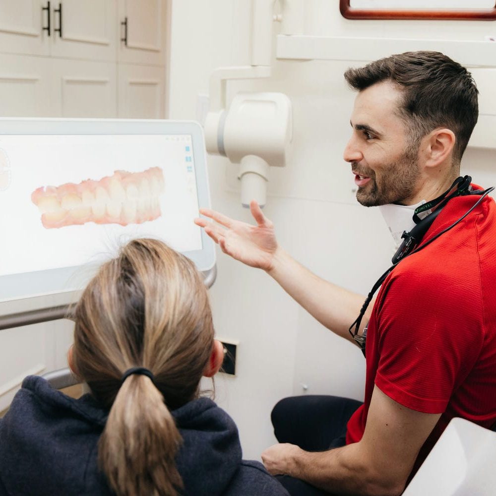 Dentist walking a patient through a 3D scan while comparing implants with other replacement options