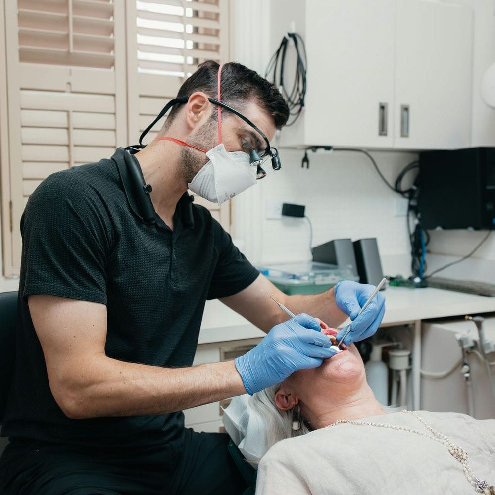 Dentist examining a patient's bonded teeth at the routine checkup that helps the repair last