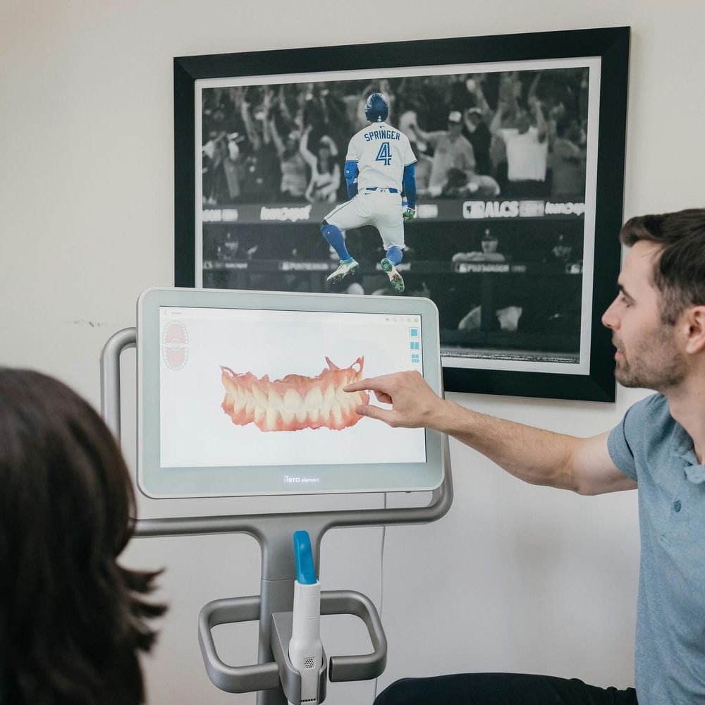 Markham dentist showing a patient a 3D scan of her teeth while discussing dental bridge options