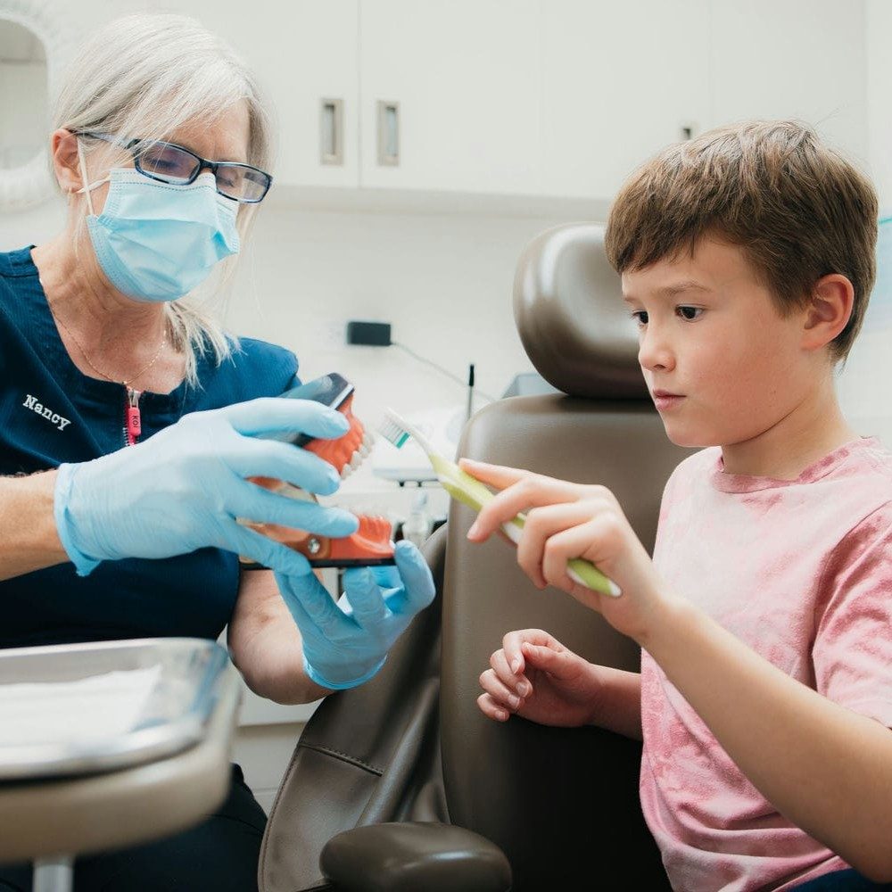 Dental hygienist explaining how to properly brush teeth to child