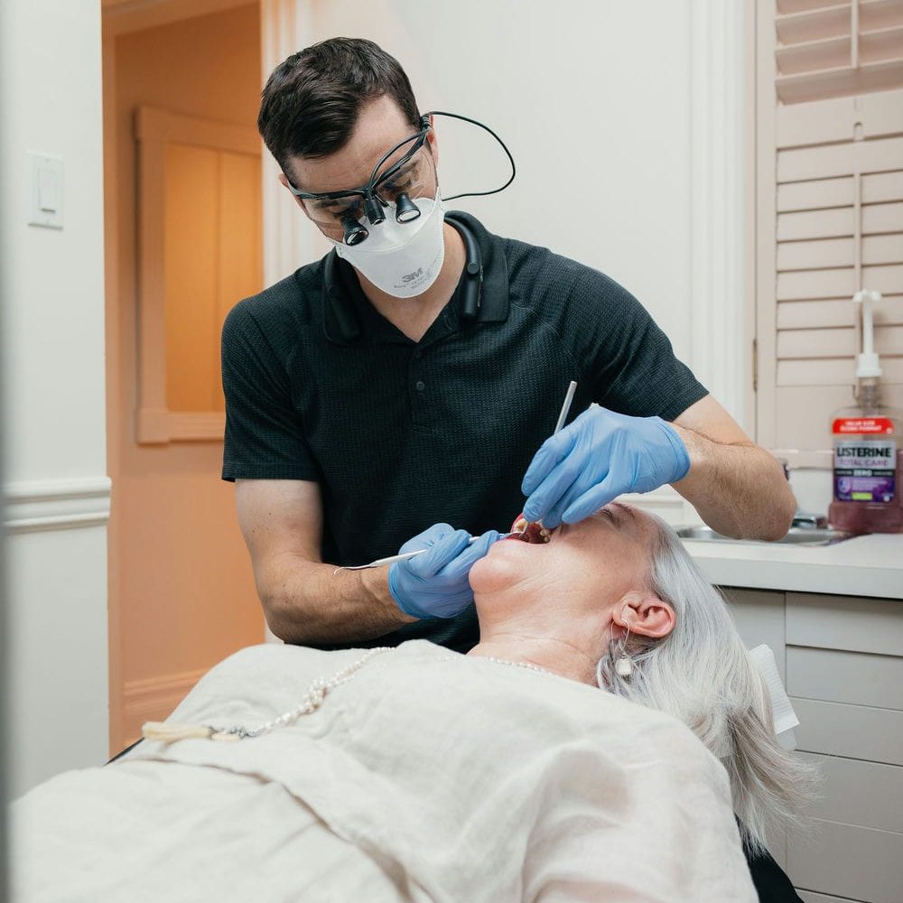 Dentist examining a patient's teeth and gums at the checkup that keeps a dental implant healthy