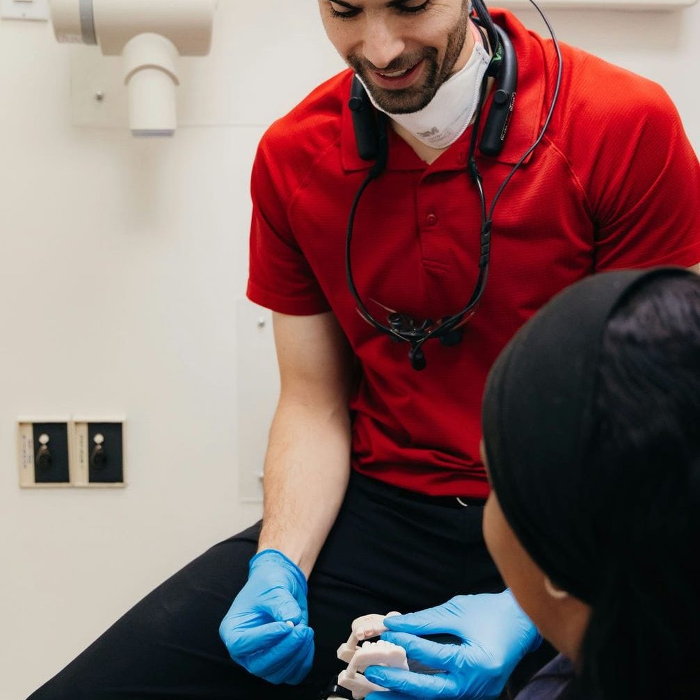 Dentist holding a dental model and restoration to show how a missing tooth can be replaced