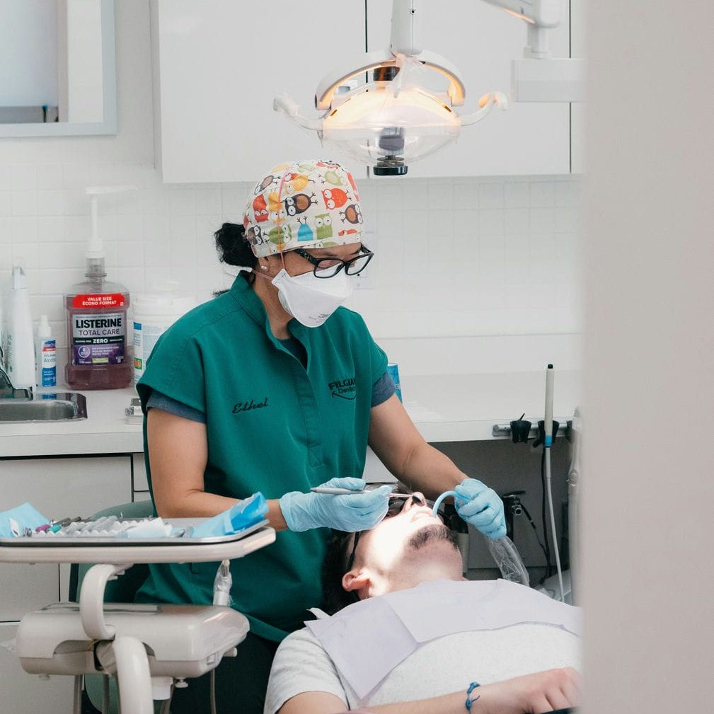 Hygienist examining a young adult patient's back molars where wisdom teeth cause crowding and pain