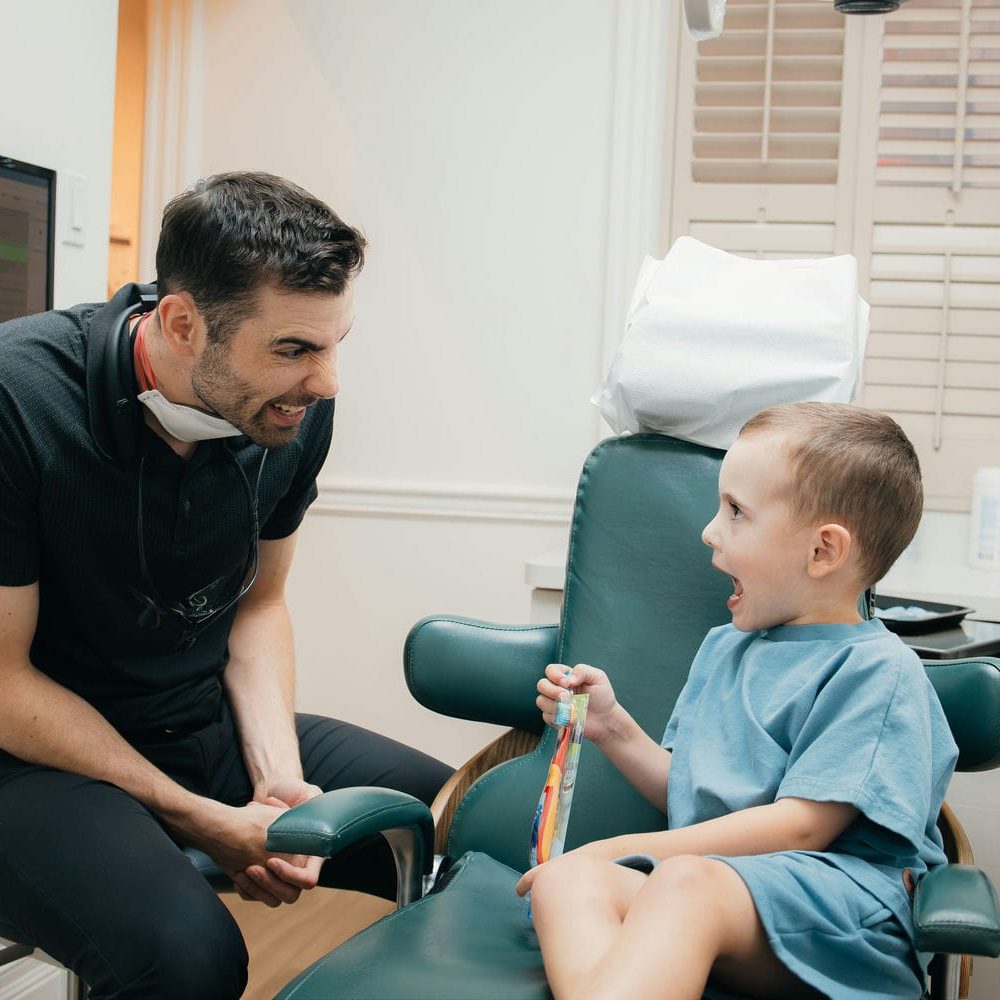 Markham kids dentist laughing with a young boy in the dental chair during a relaxed visit