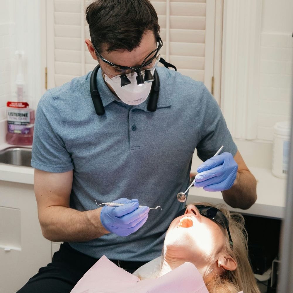 Dentist checking a patient's teeth and gums with a mirror and scaler during a regular cleaning
