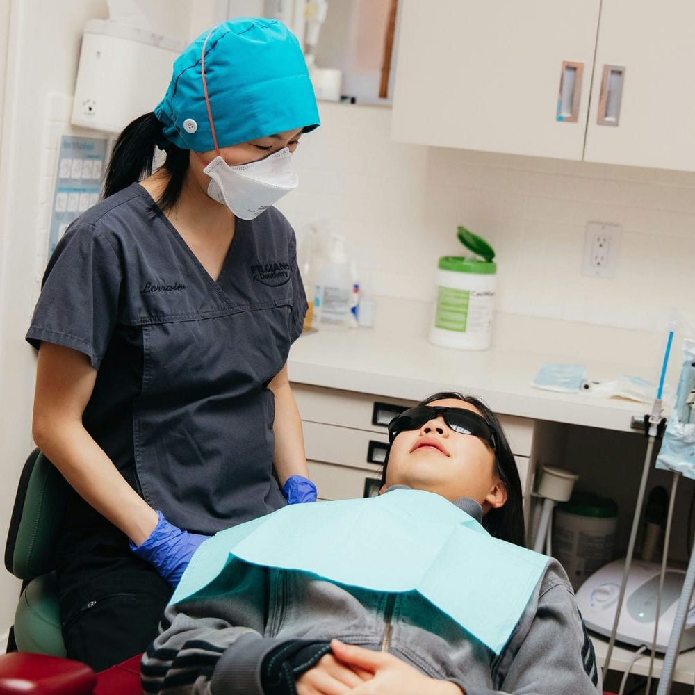 Relaxed patient wearing protective eyewear as the hygienist begins her dental cleaning appointment