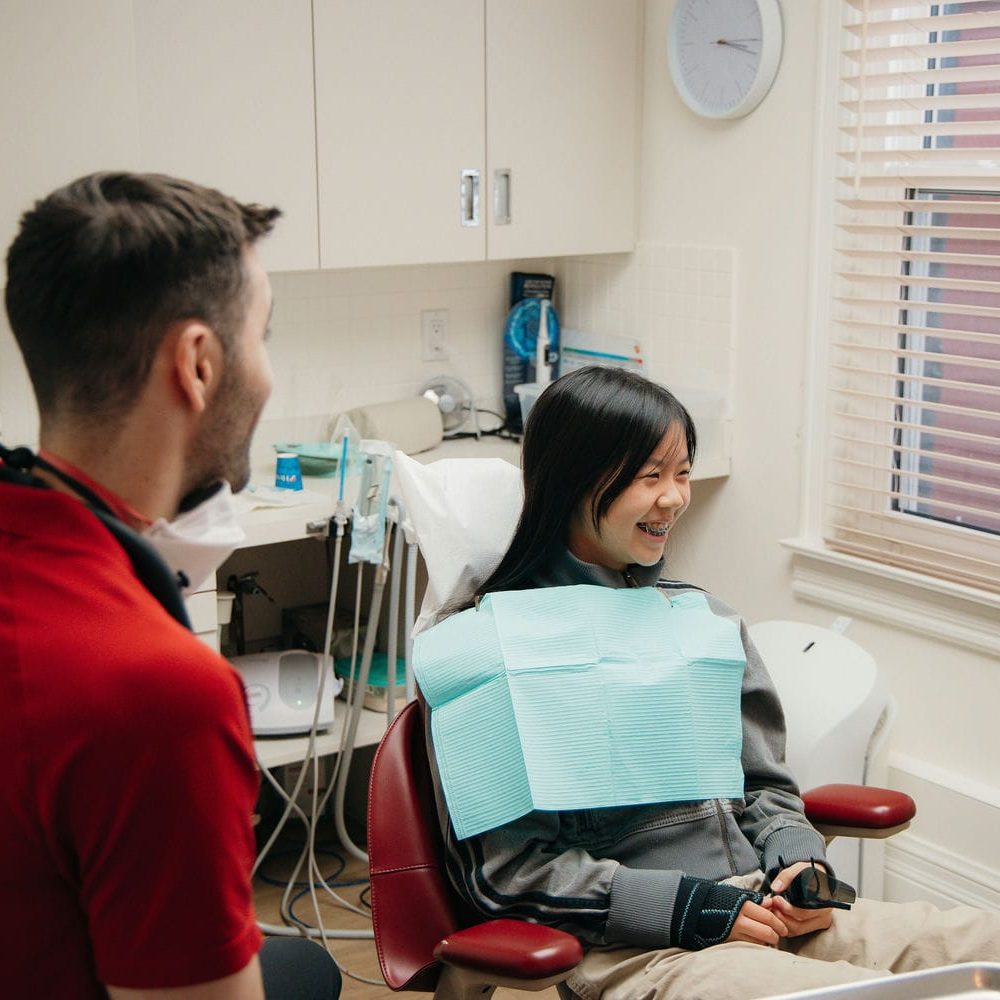 Young patient smiling with her dentist while going over wisdom tooth recovery and aftercare